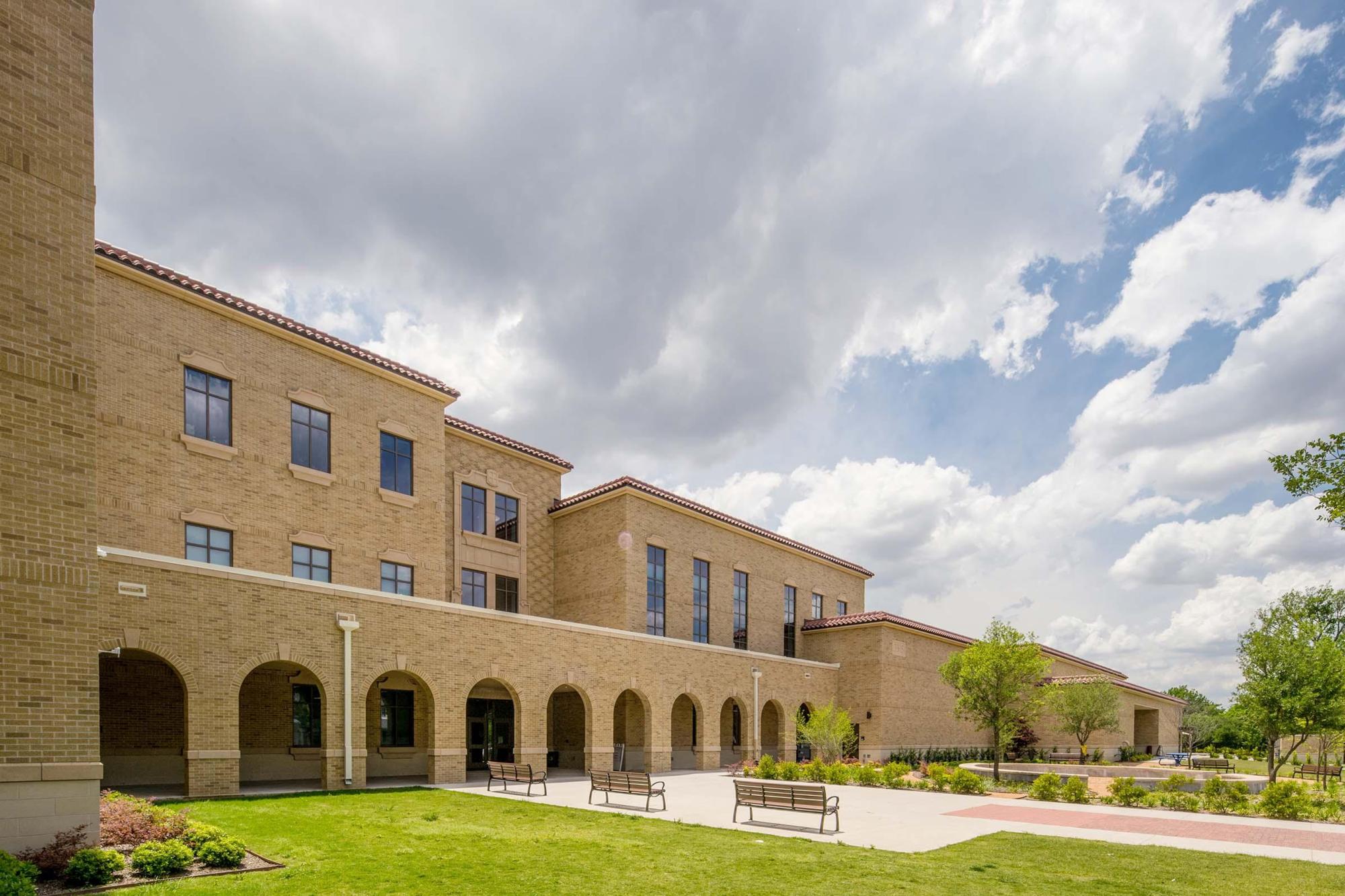 Image of the whole of University Park Elementary School, showcasing brown brick and green lawns under a cloudy yet blue sky
