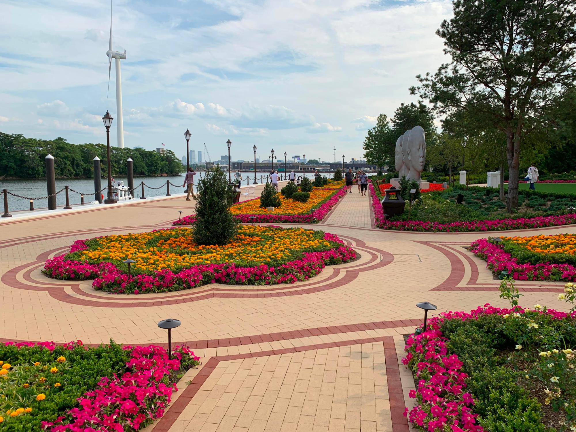Image of the red and beige brick walkway along the riverfront of the Encore Casino with flowers between the walks