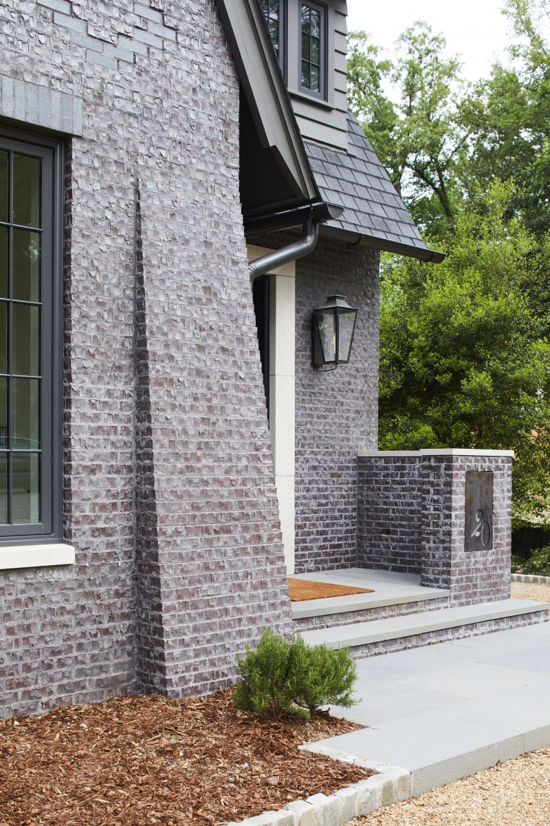 Corner of a brick home with trees in background