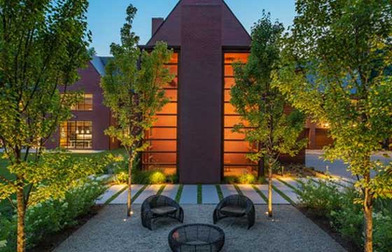 An outdoor patio with brick, chairs, and trees