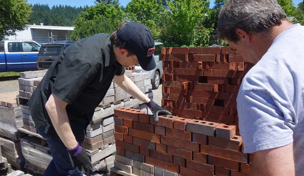 Two men inspecting foundation of brick wall