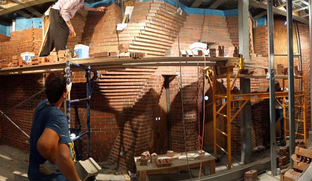 Two men inspecting brick structure with scaffolding.