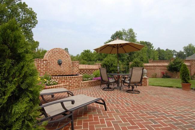 Image of a paved brick patio with chairs, grass, and trees