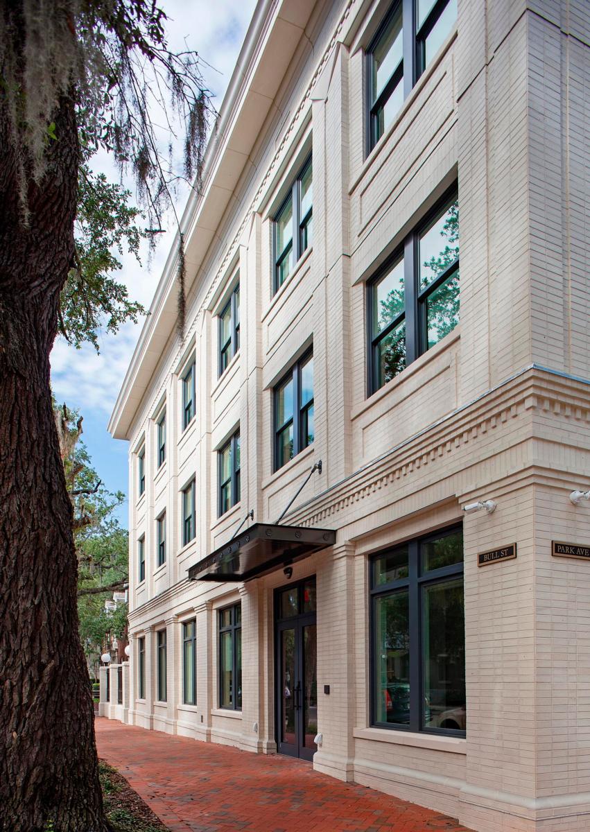 Image of the light colored bricked exterior of the windowed and surrounded by trees Bouhan Falligant