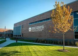 Image of the red bricked exterior of School District 59, featuring blue skies and green grass