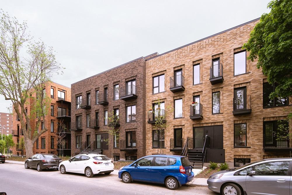 Image of the red brick 5551 Wellington building with a tree and cars parked outside