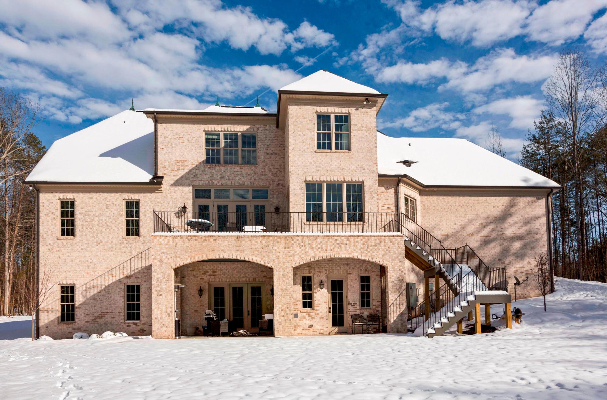 An exterior photo of the Cedar Hollow Road Residence from the rear in winter, with snow on the ground and roof