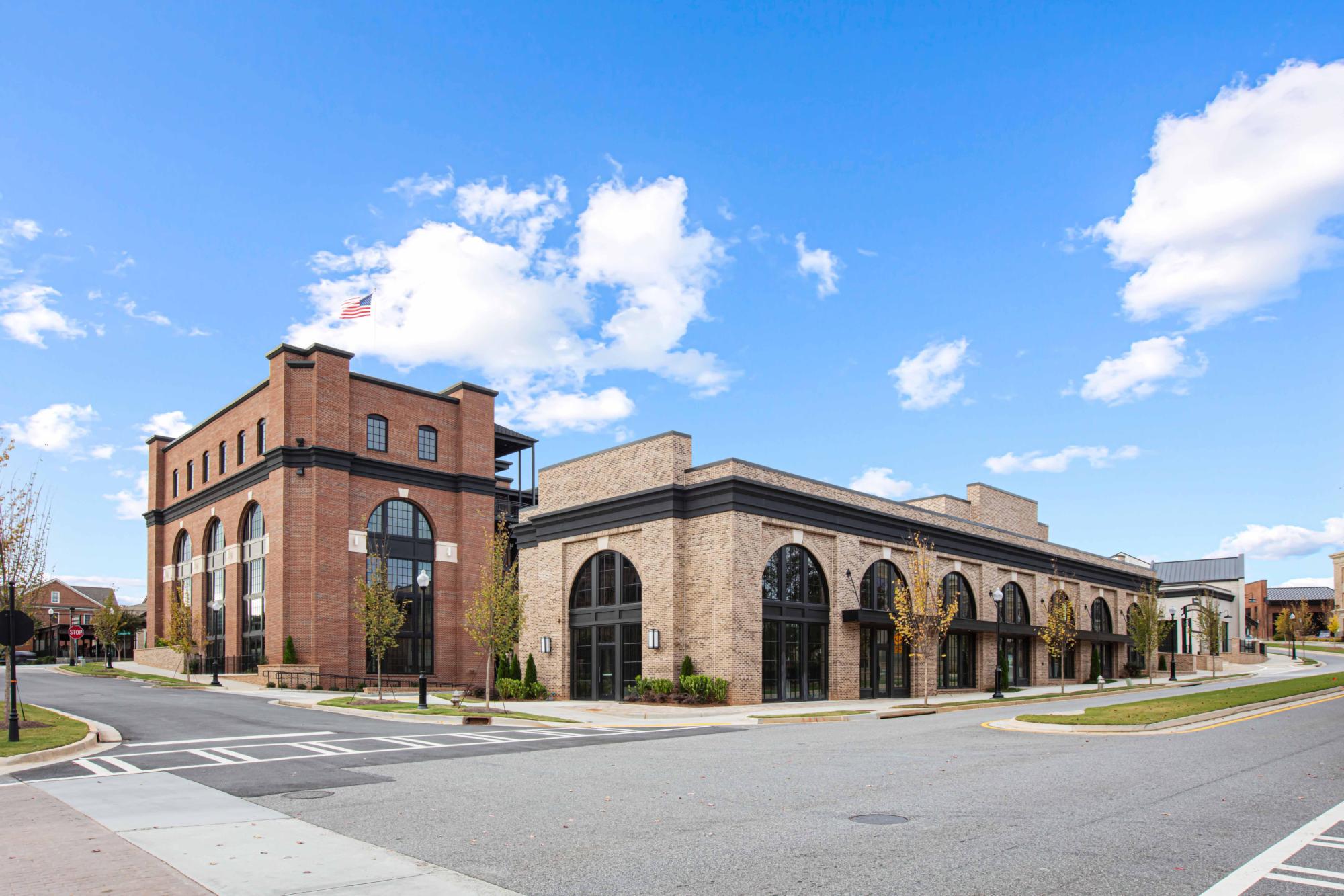 The Crabapple Marketplace, built of brick and surrounded by roads under a blue, partly cloudy sky.