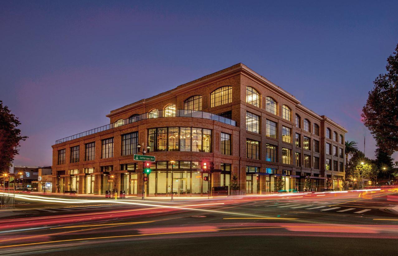 2075 Broadway, fully bricked and illuminated, stands tall on a city block in the afternoon