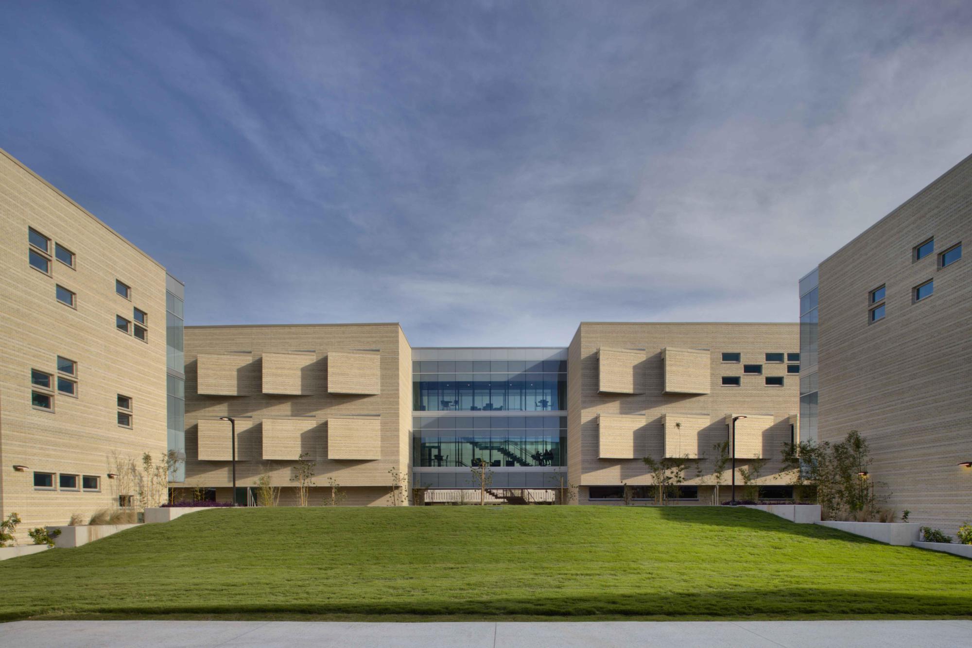 A green grass yard is ringed by the beige bricked Del Mar College