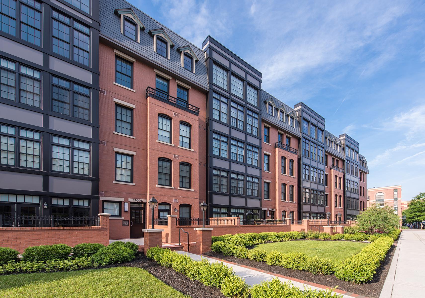 Exterior photograph of Gaslight Square with white walkway, green shrubbery and grass, and the bricked building with windows