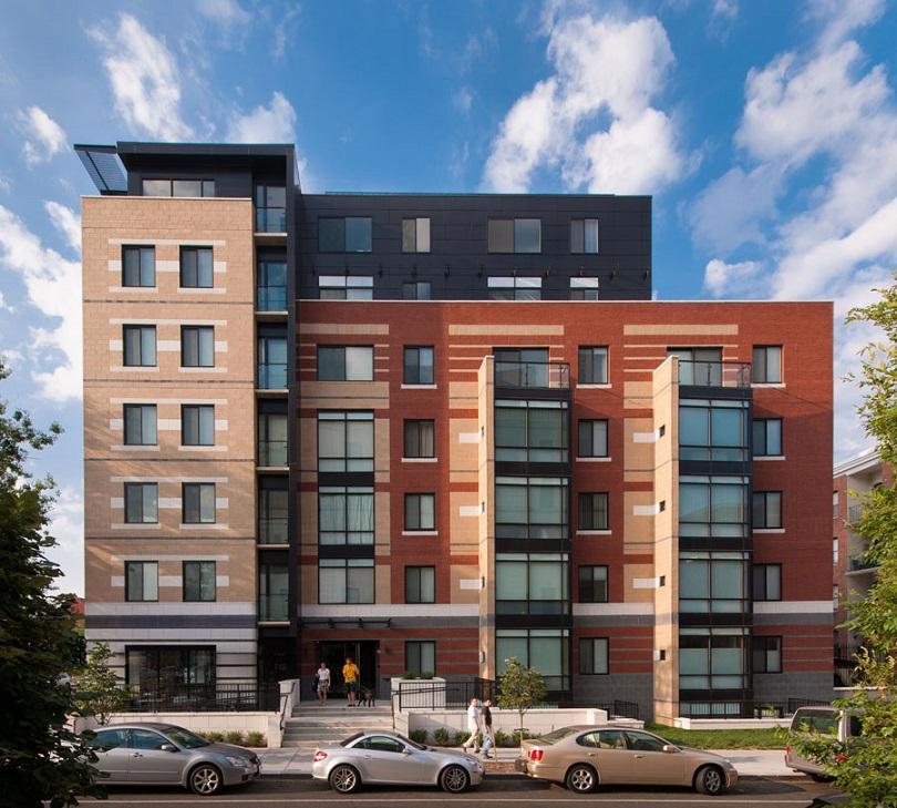 Photograph from the rear of The Aston showcasing the building and parking lot with cars parked within