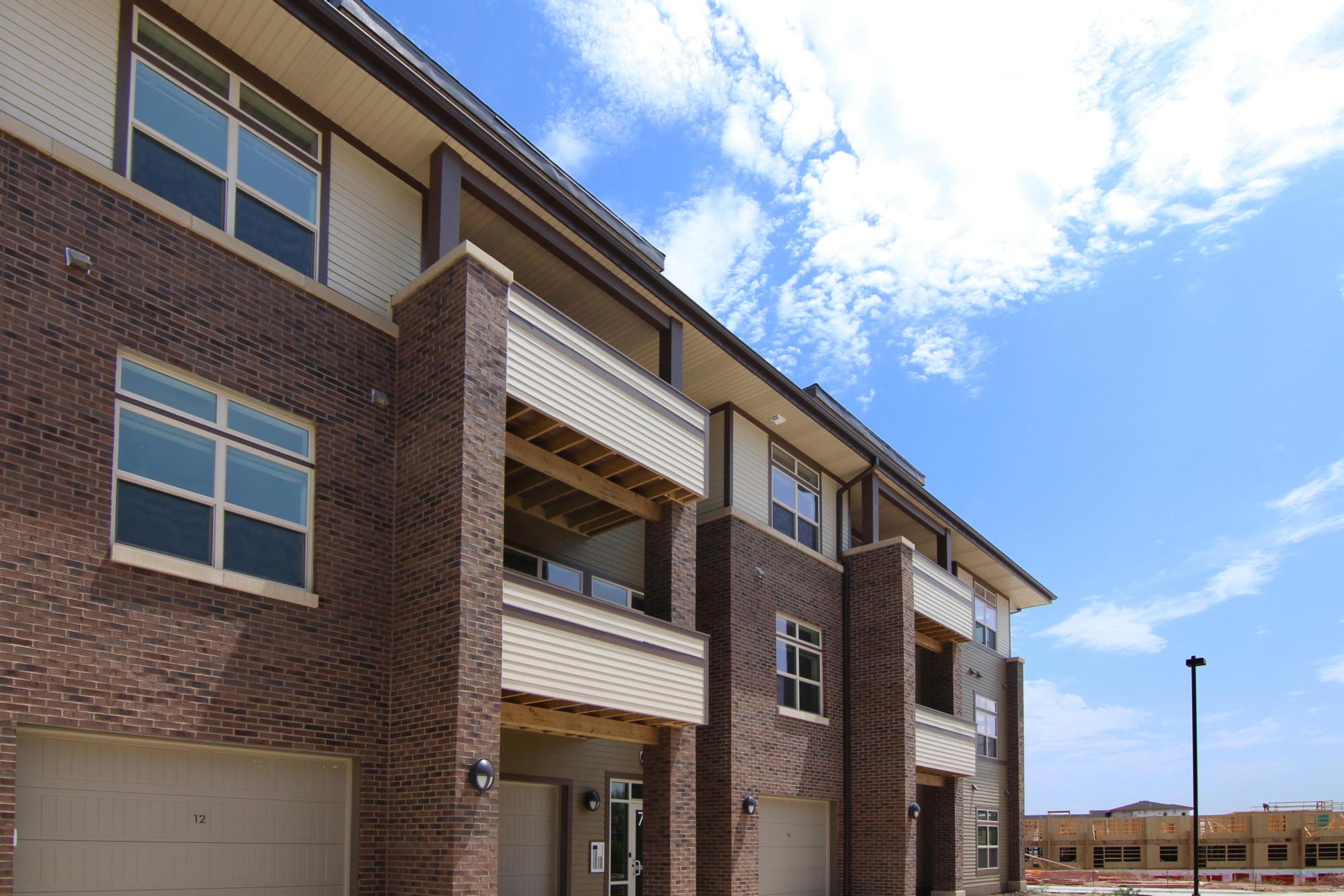 Exterior photograph of the Brookside Apartments at Fallbrook with green grass and blue skies