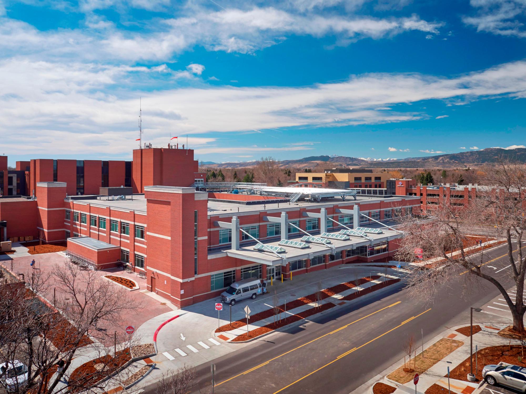 The exterior of the bricked Poudre Valley Hospital with a blue, white clouded sky above it
