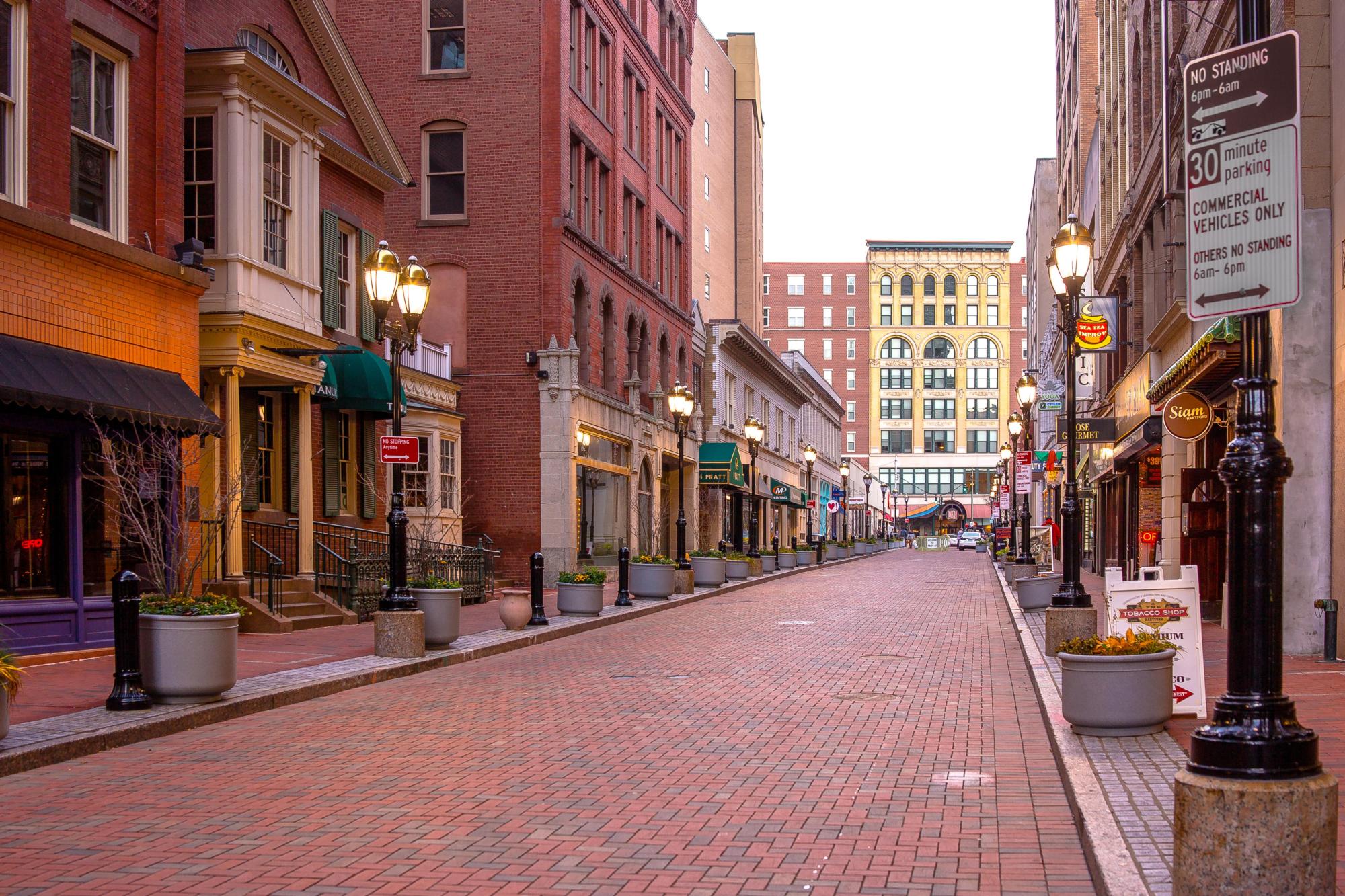 Pratt St. Historic District in midafternoon with bricked walkway, buildings, and lit street lamps