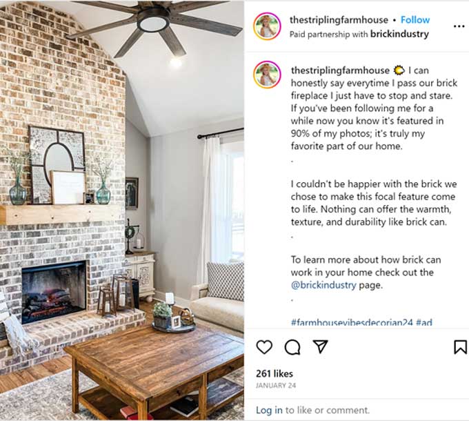 The white interior of a home's den with a brick fireplace